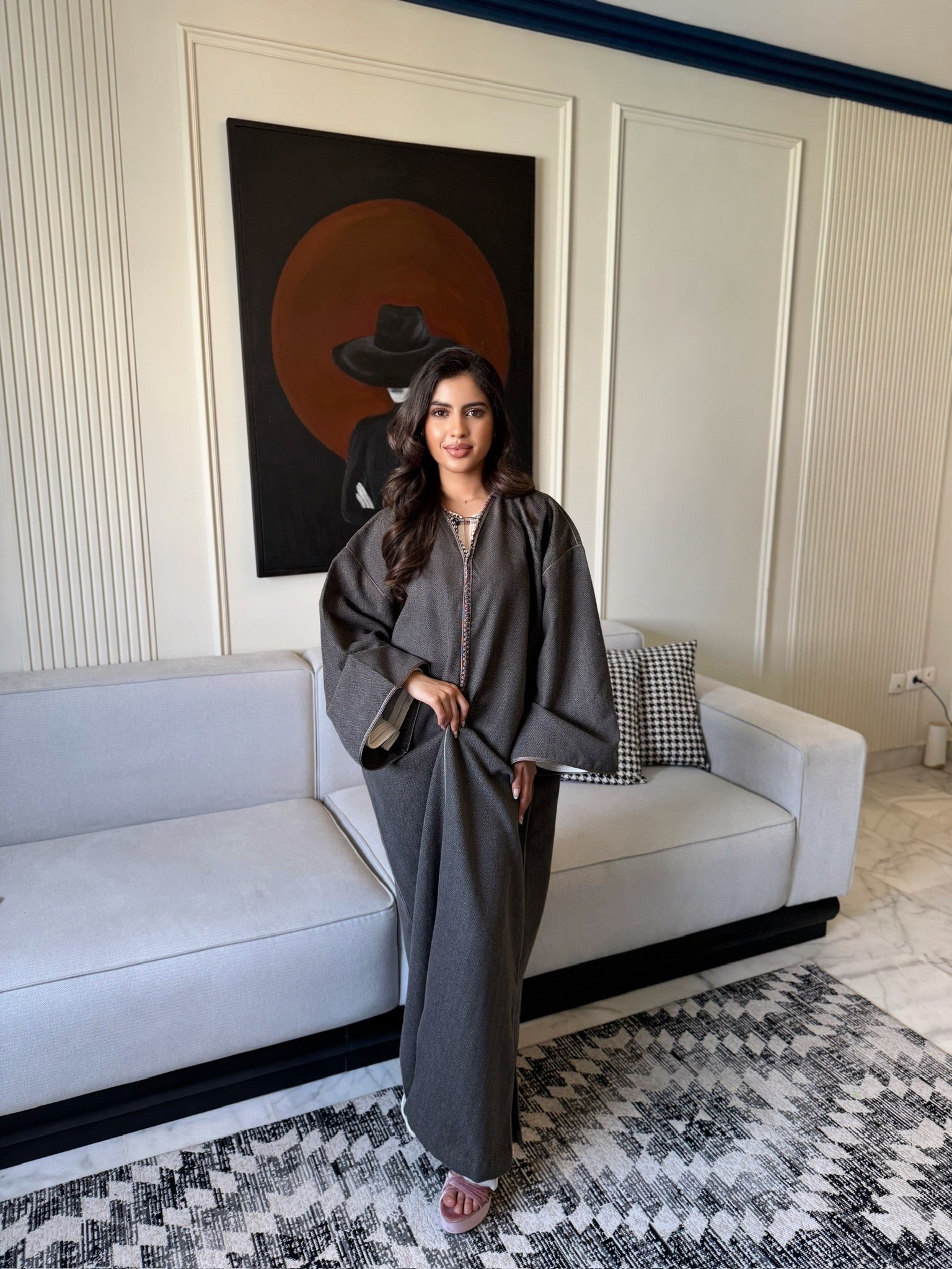 Woman wearing a dark grey caftan with a flowing silhouette and wide sleeves