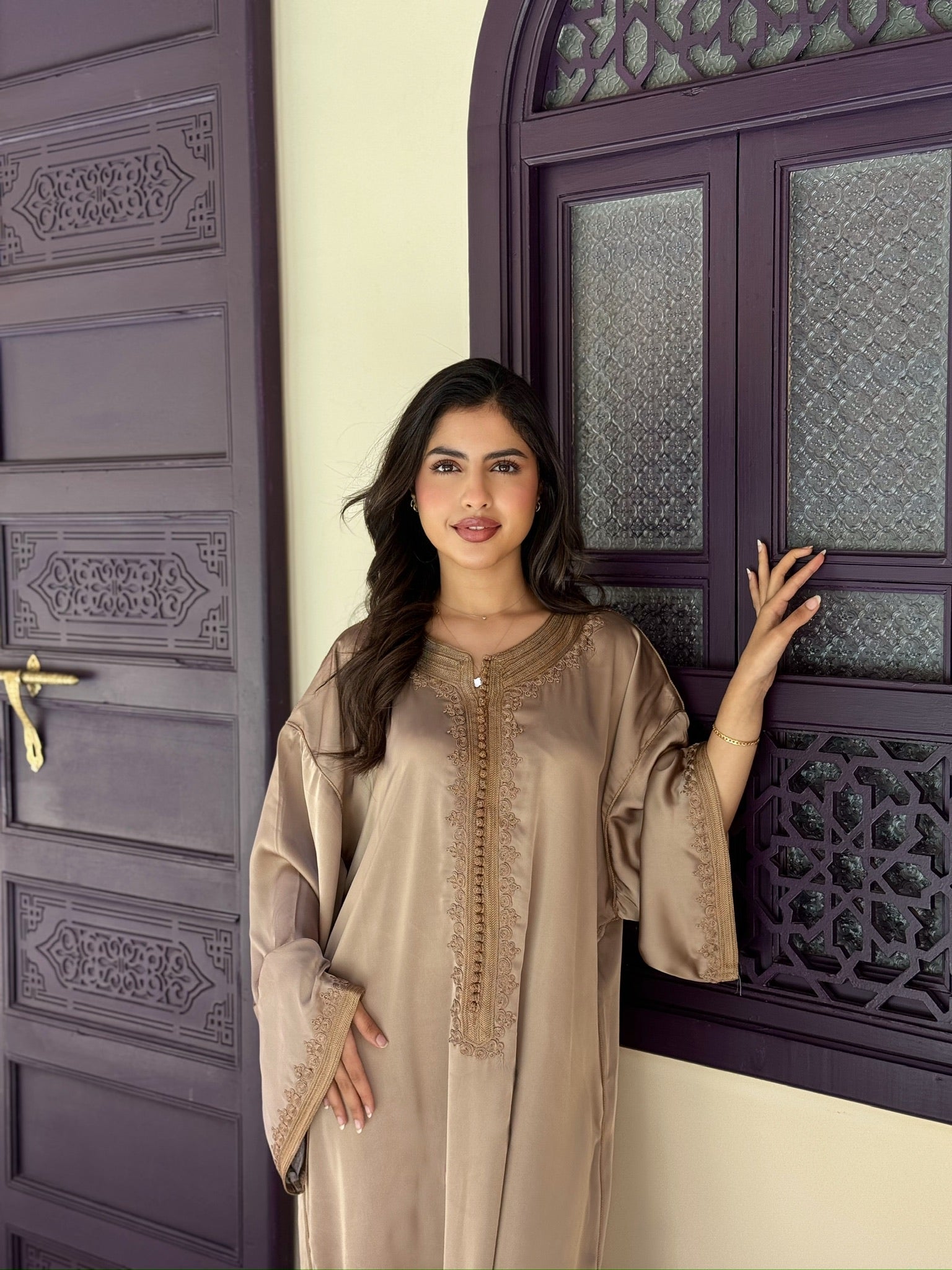 Woman wearing a taupe gandoura with delicate embroidery and flowing sleeves