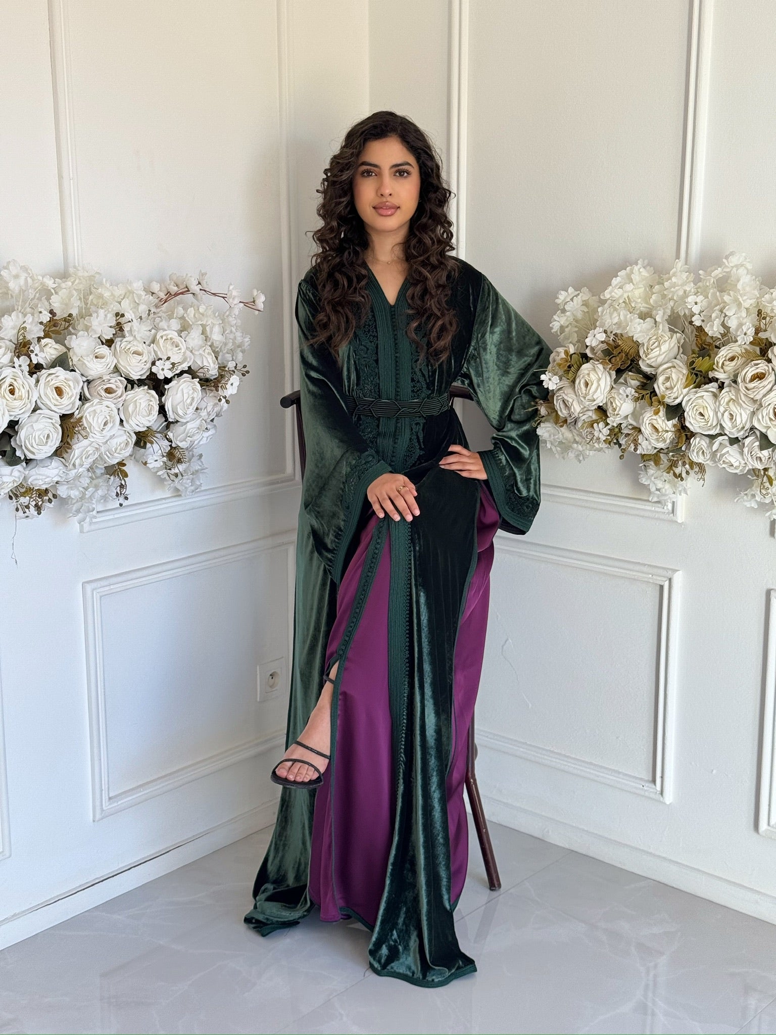 Full view of the dark green Caftan Nancy featuring purple detailing in a refined setting.