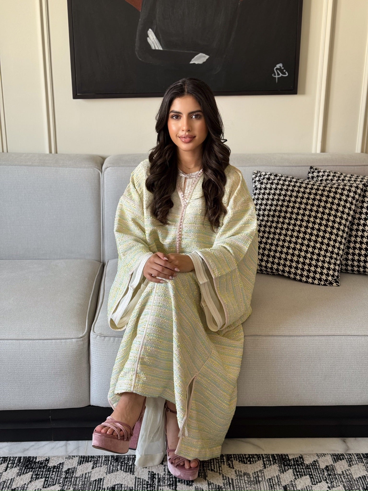 Woman wearing a sage green caftan with wide sleeves and elegant detailing