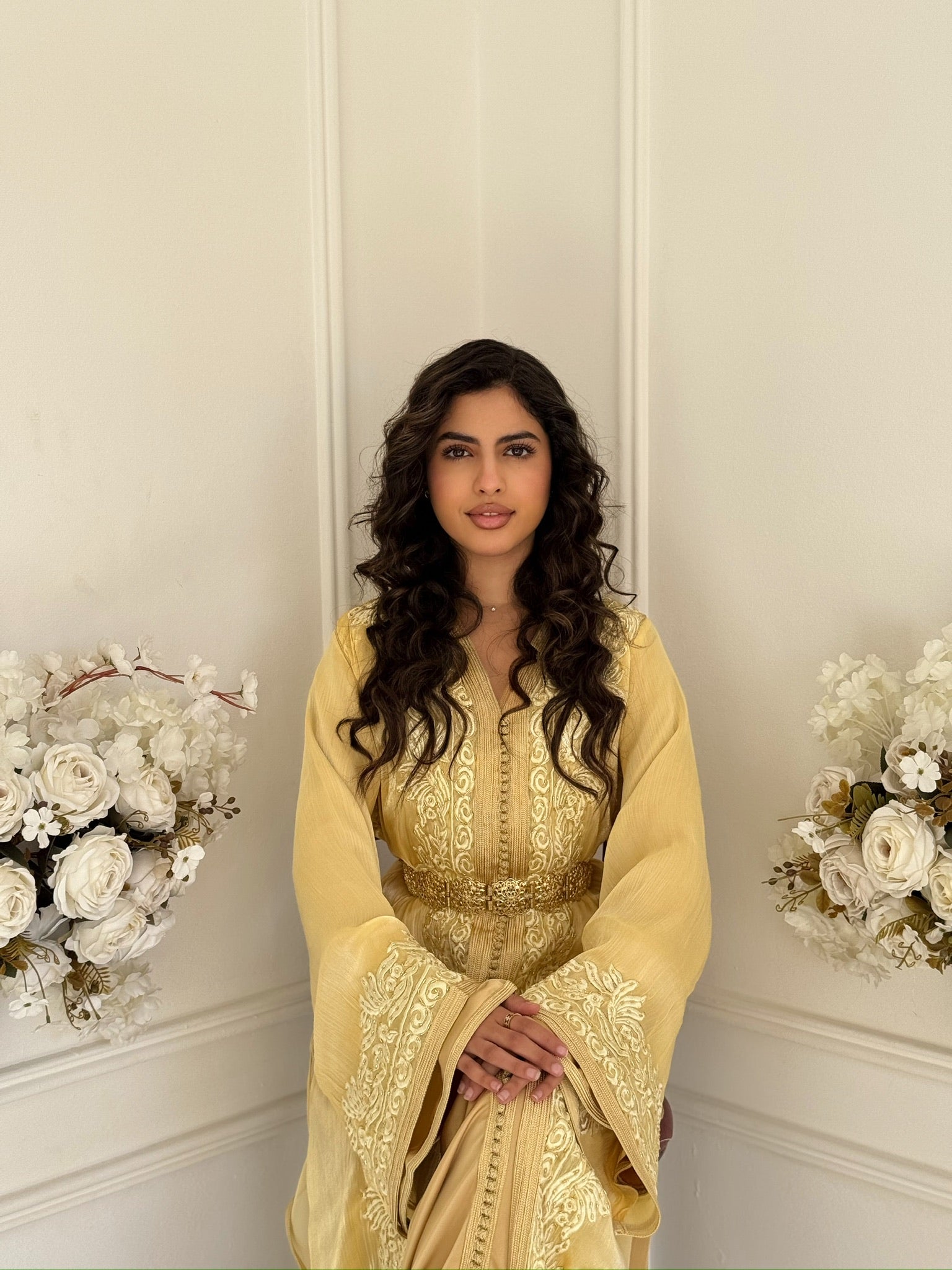 Soft gold Moroccan takchita made from organza with elegant embroidery displayed in a refined interior.