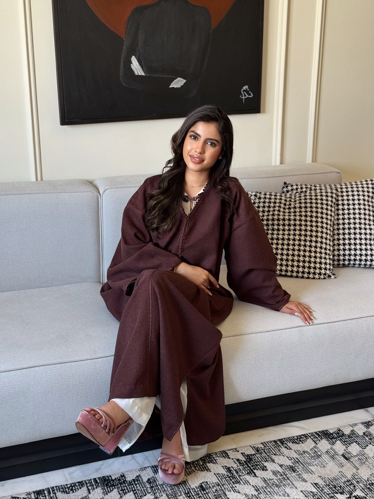 Woman wearing a burgundy caftan with wide sleeves and elegant detailing