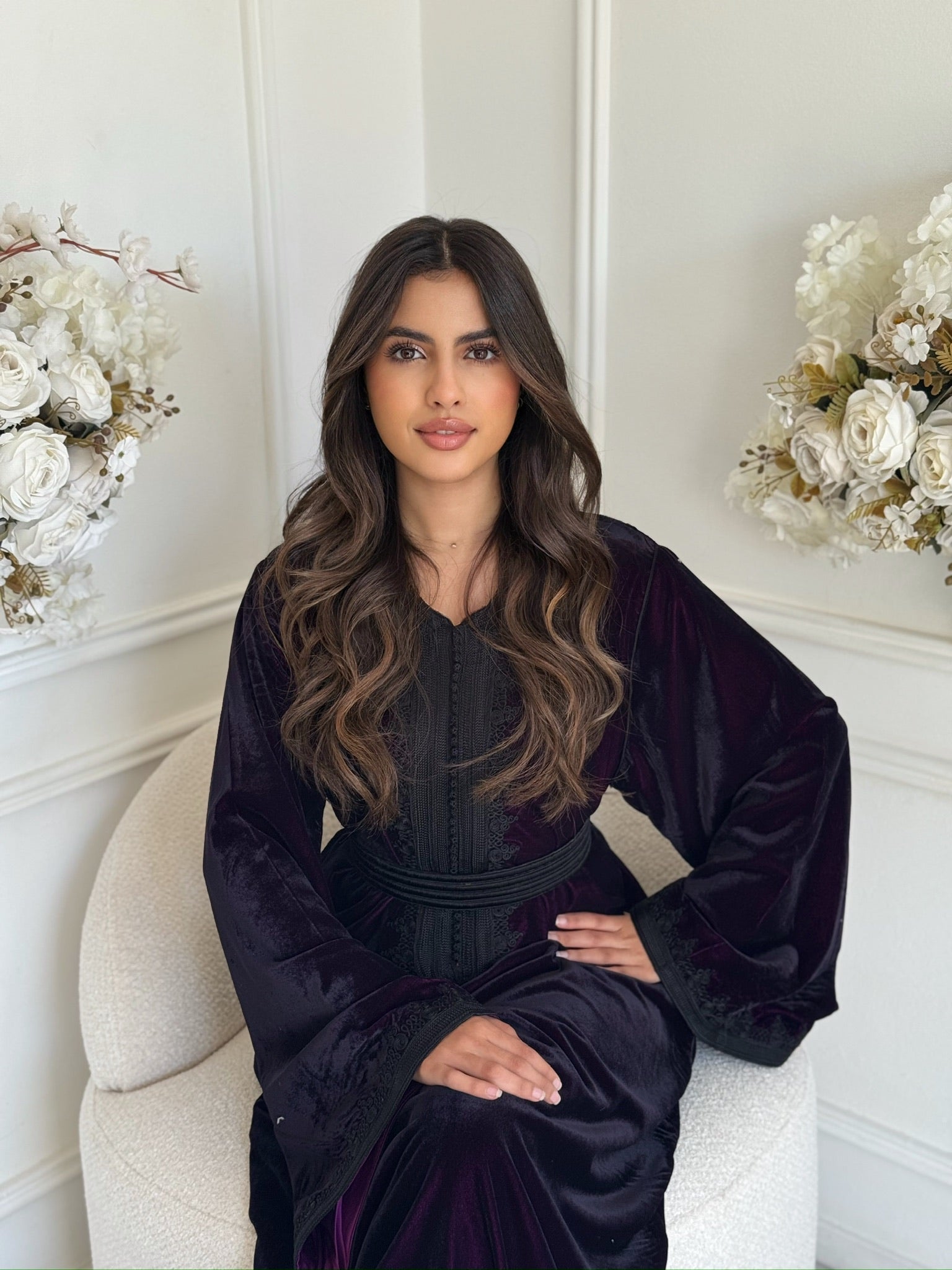 Woman wearing a deep-purple Moroccan caftan sitting in a chair